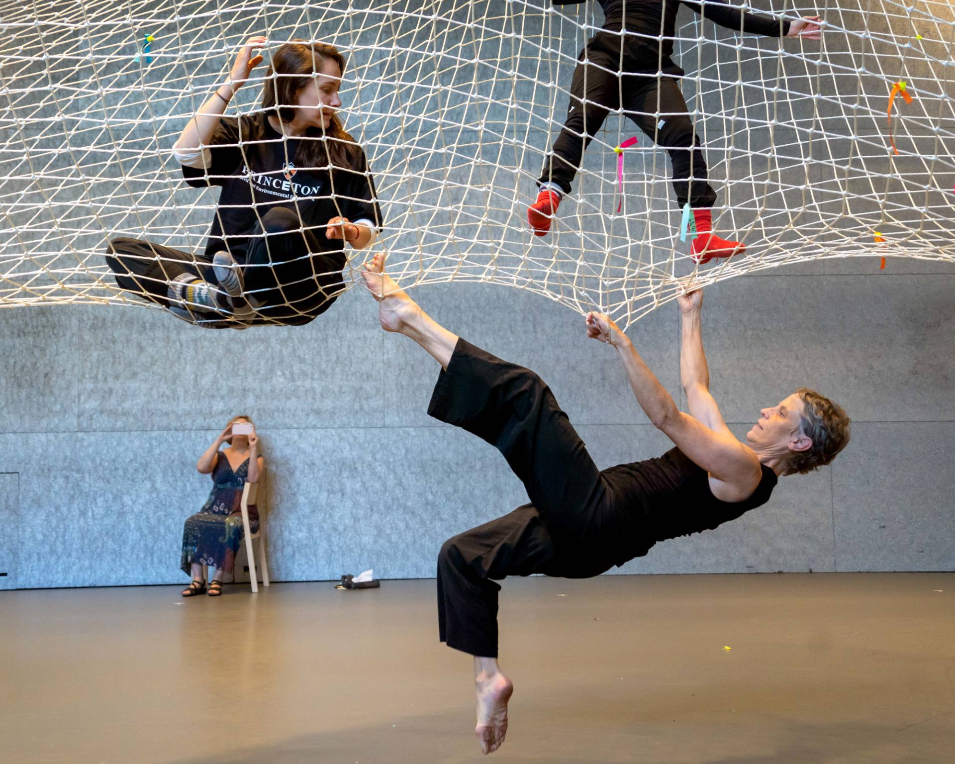 Group of people sitting and hanging on a large net.